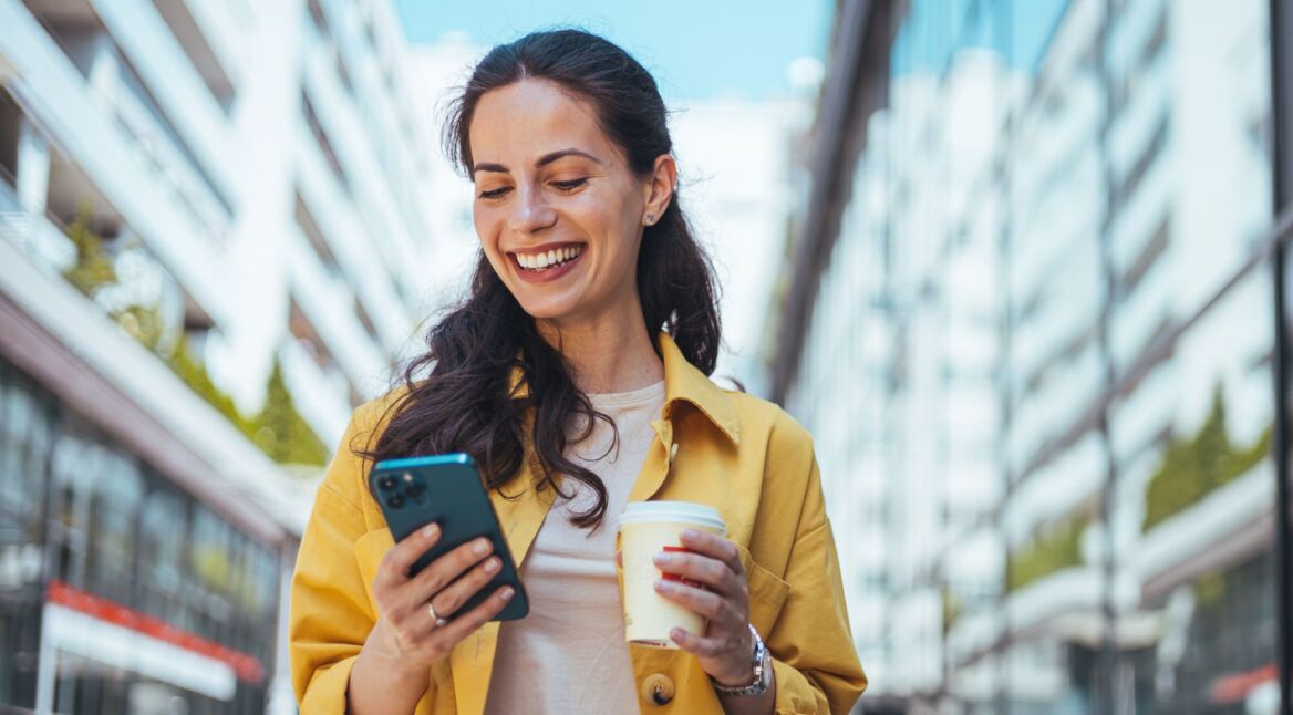 Lächelnde Frau passt auf iPhone die E-Mail-Adresse ihres Apple Accounts an