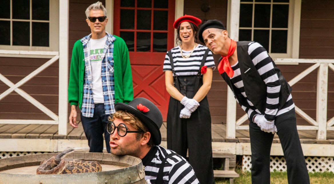 Drei Personen schauen einem Mann zu, der sein Gesicht vor eine Schlange hält. Ein Stunt aus Jackass Forever (Jackass 4)