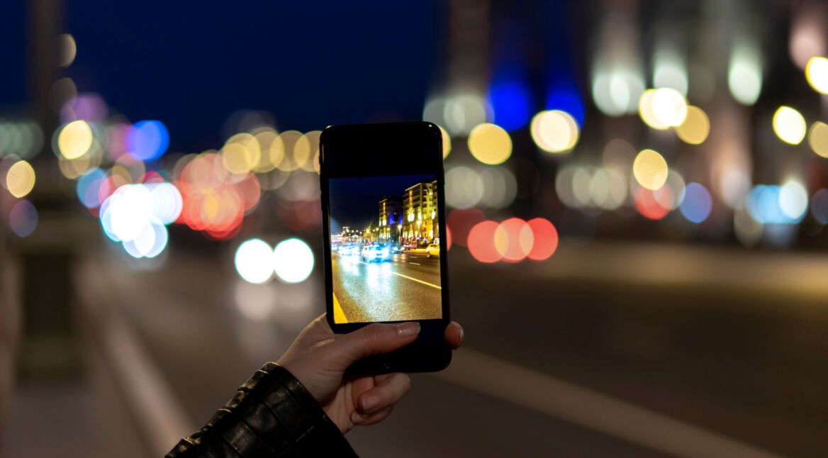 Frau macht mit dem Smartphone ein Foto bei Nacht