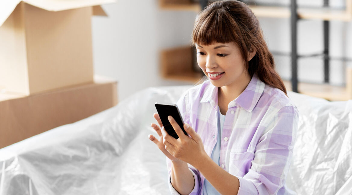 Frau guckt lächelnd auf ihr Smartphone