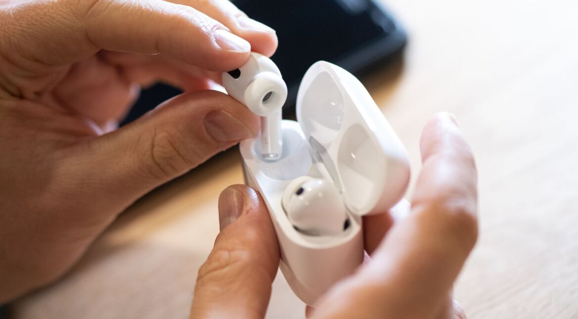 Ein Mann zieht AirPods Pro von Apple aus dem Ladecase.