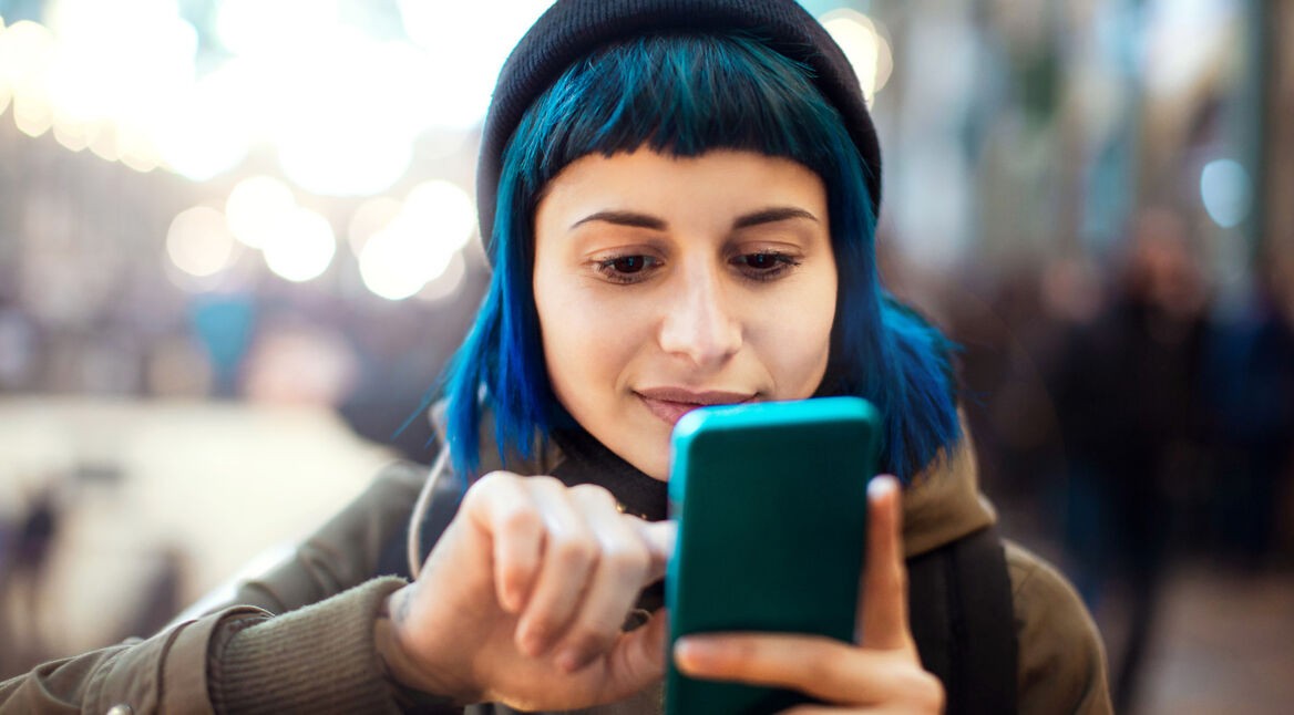 Eine junge Frau tippt auf ihrem Smartphone.