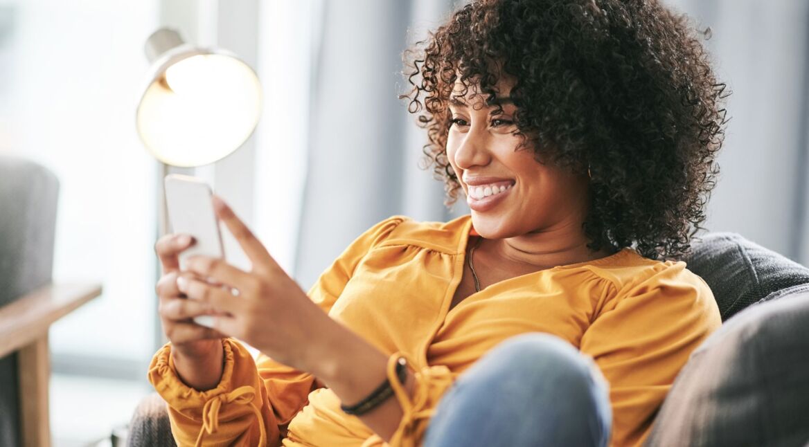 Frau schaut lächelnd auf ihr Handy.