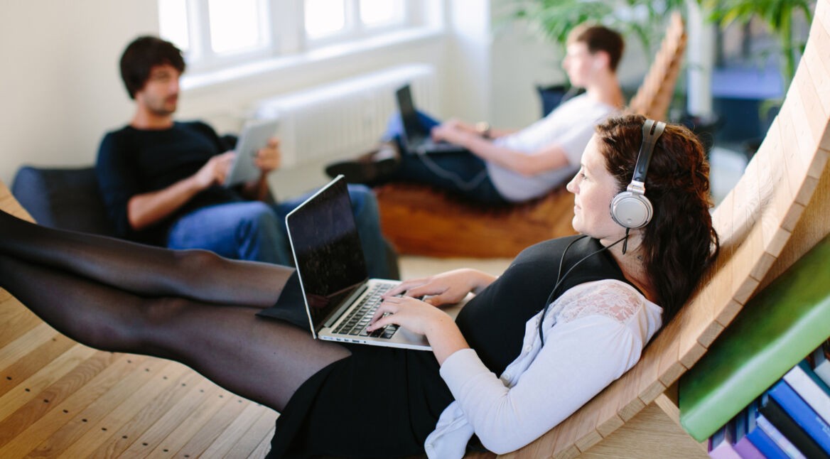 Drei Leute hören Musik an Laptops und Tablets