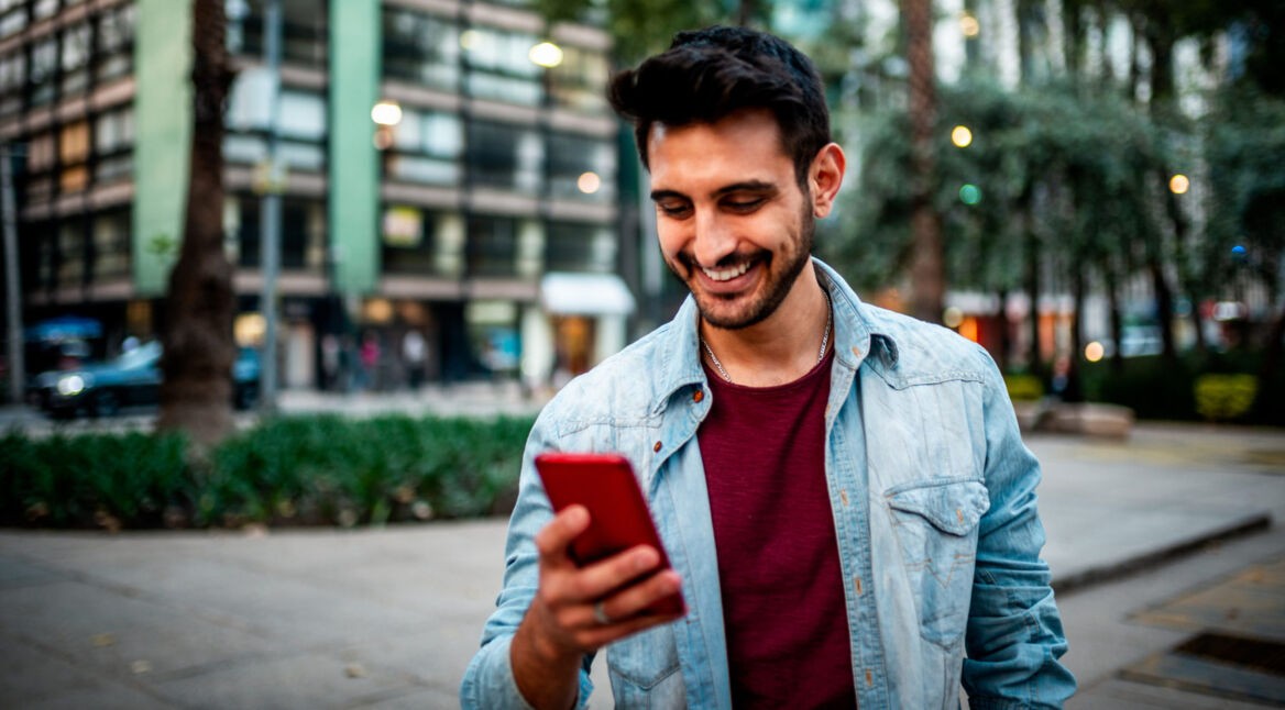 Mann ist unterwegs in der Stadt und freut sich über iPhone-Tricks.
