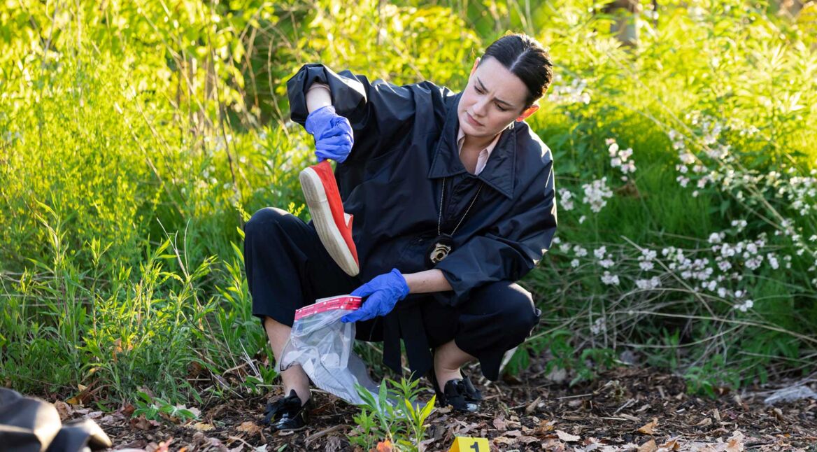 Eine Ermittlerin sammelt einen Schuh an einem Tatort ein