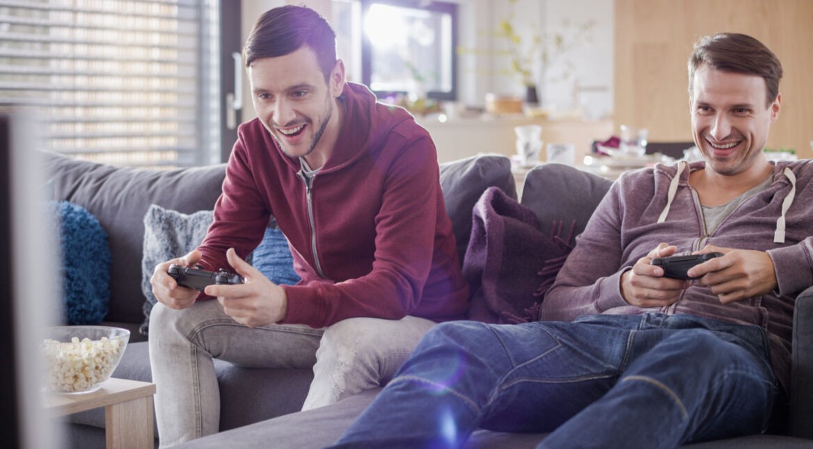 Zwei Männer spielen an der PlayStation.