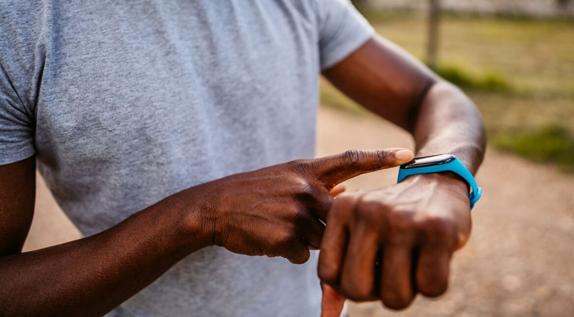 Mann trägt einen blauen Fitnesstracker am Handgelenk.