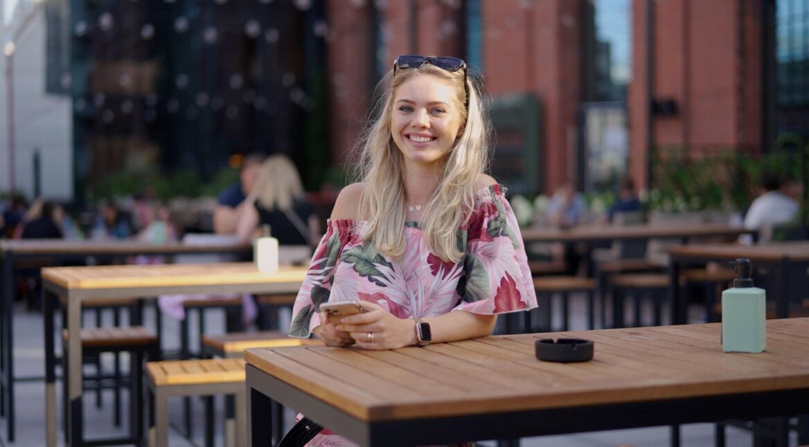 Junge Frau mit Handy im Straßencafè