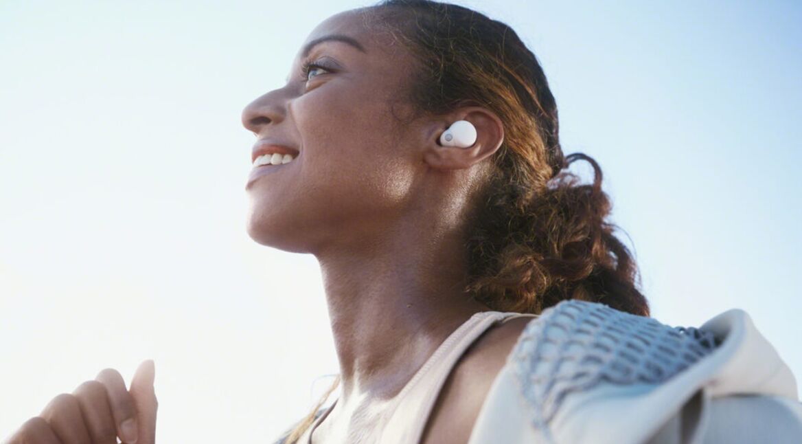 Lächelnde Frau unter freiem Himmel trägt Sony-Kopfhörer LinkBuds S