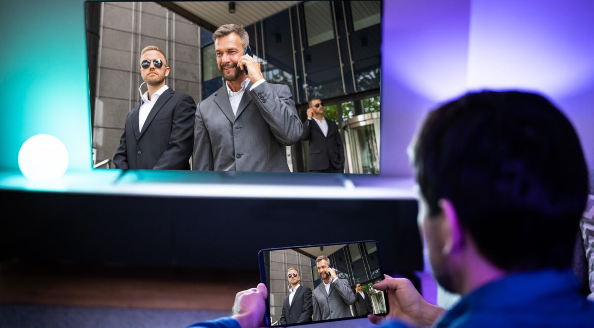 Mann streamt Tablet-Inhalt auf Fernseher