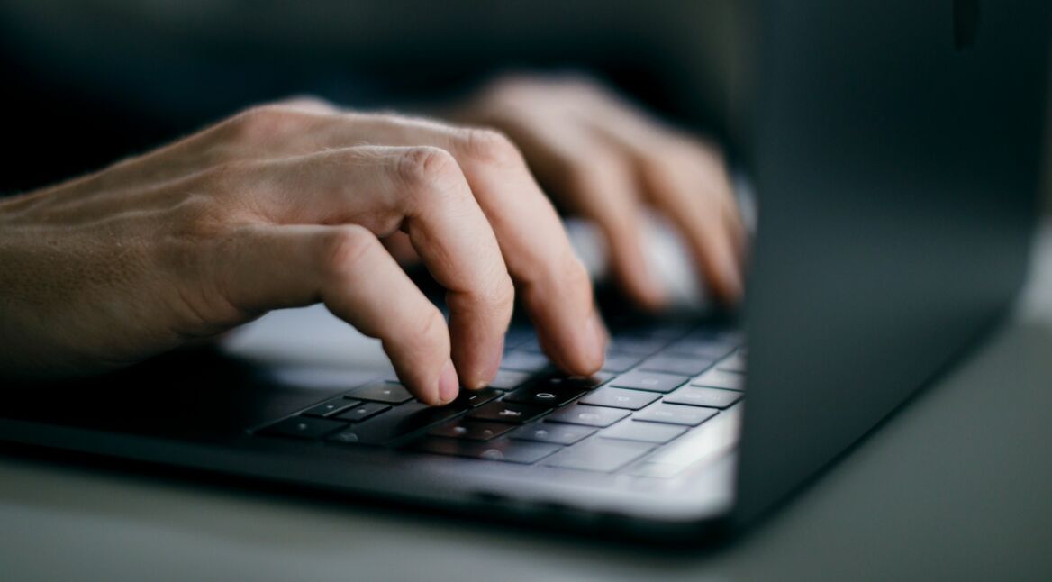 Männliche Hände tippen auf MacBook-Tastatur
