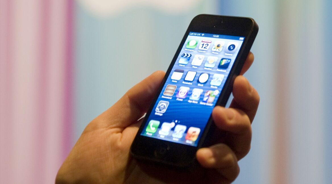 Hand hält iPhone 5 vor bunt gestreifter Wand