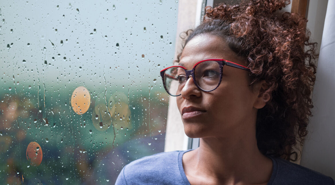 Trauernde Frau schaut aus dem Fenster