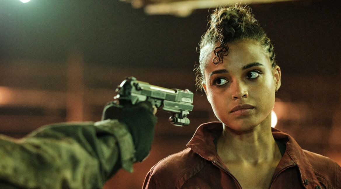 Eine Frau guckt in die Mündung eines Revolvers