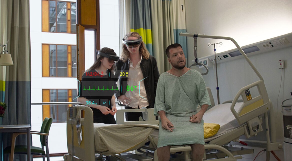 Ein Hologramm-Patient wird von zwei Medizin-Studierenden in einem Behandlungszimmer untersucht