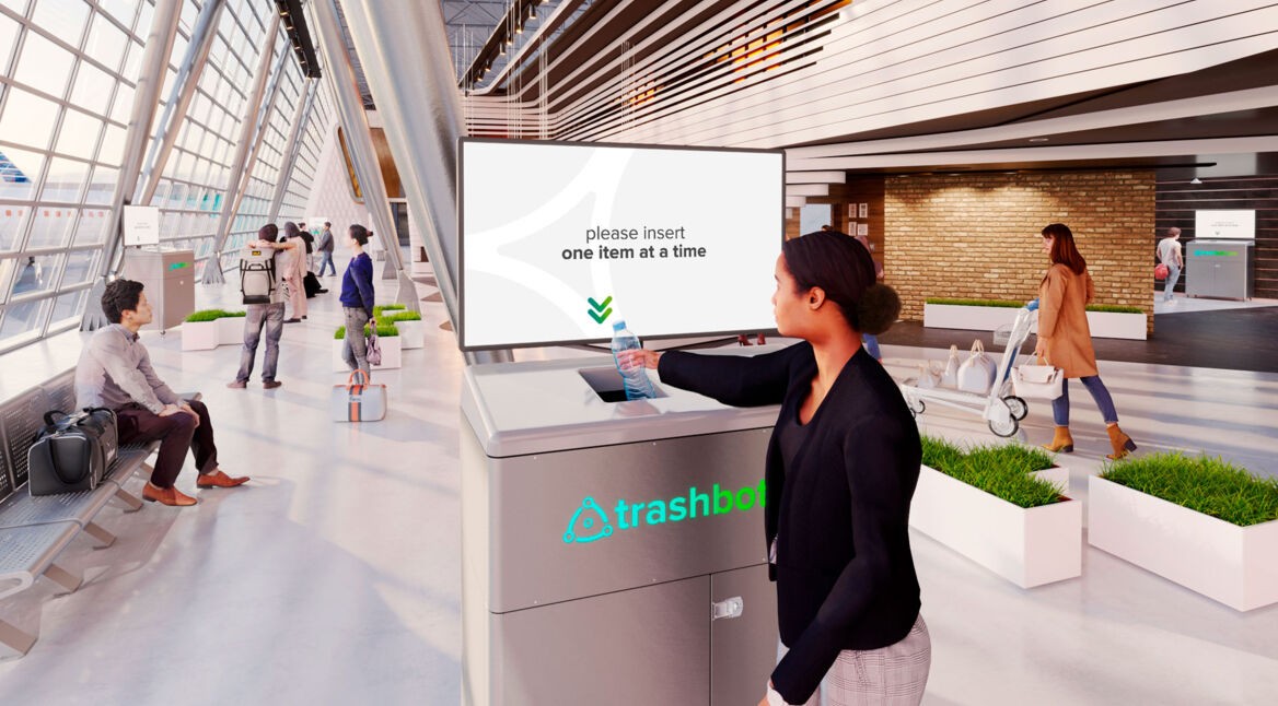 Eine Frau wirft eine Flasche in den smarten Mülleimer Trashbot