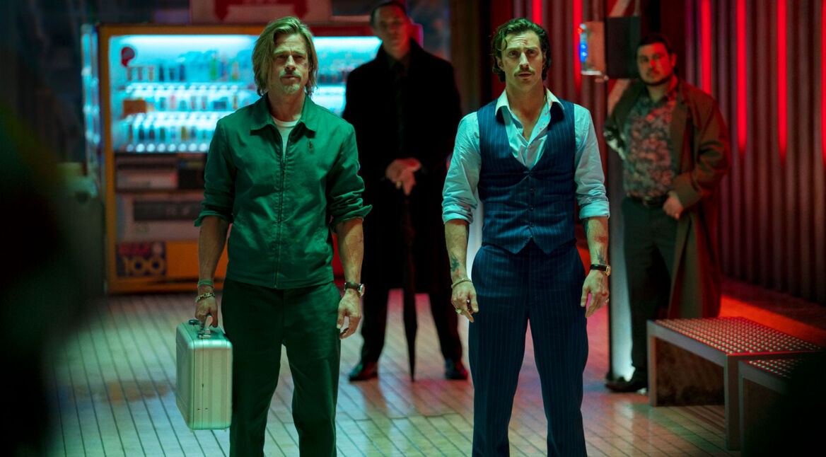 Zwei Männer stehen mit einem Koffer in einem Bahnhof