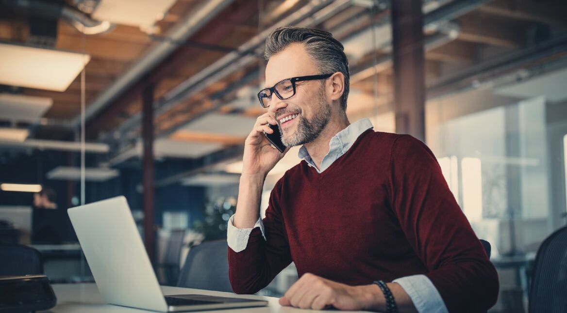 Mann telefoniert vor dem Laptop