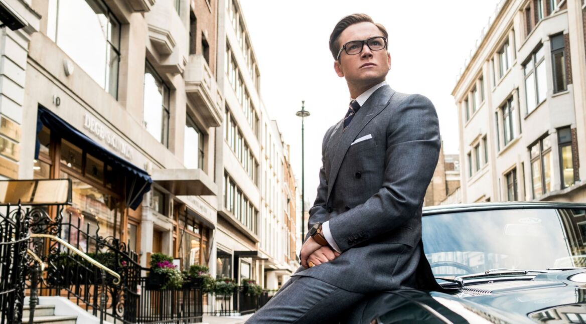 Junger Mann lehnt lässig an einem Sportwagen