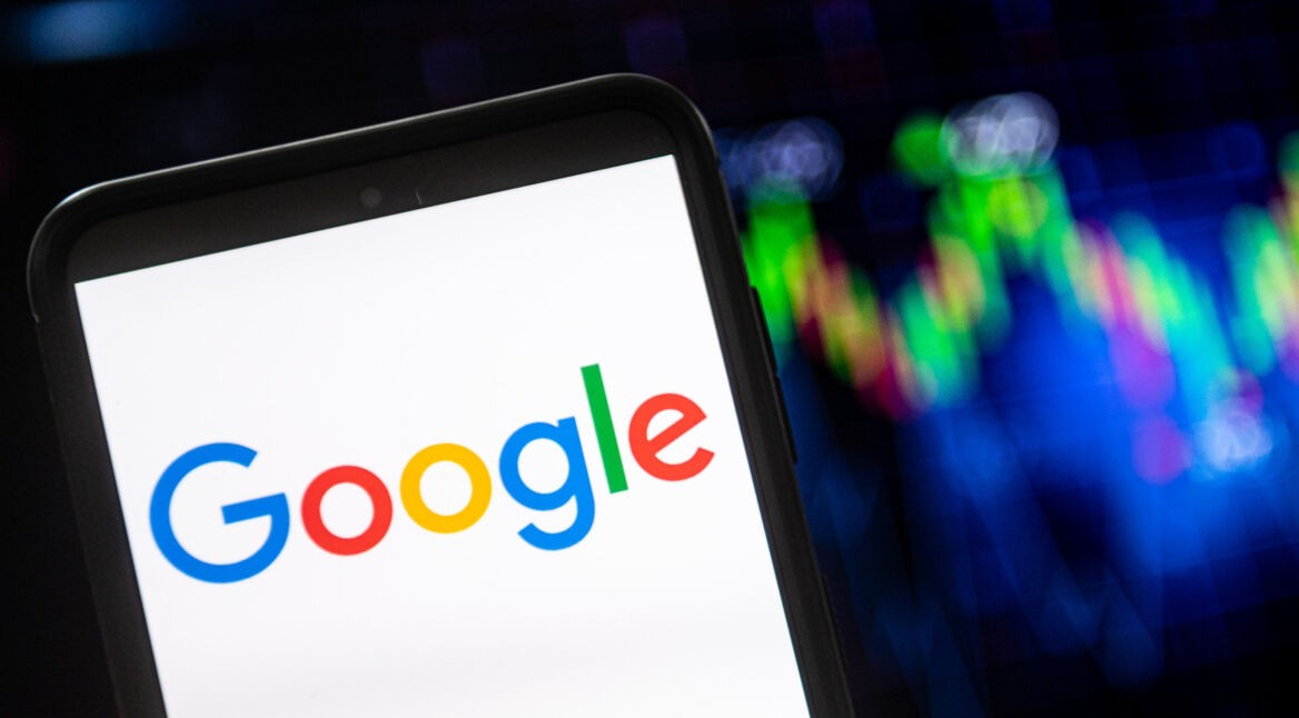 Smartphone mit Google-Logo auf dem Display vor bunten Lichtern im Hintergrund