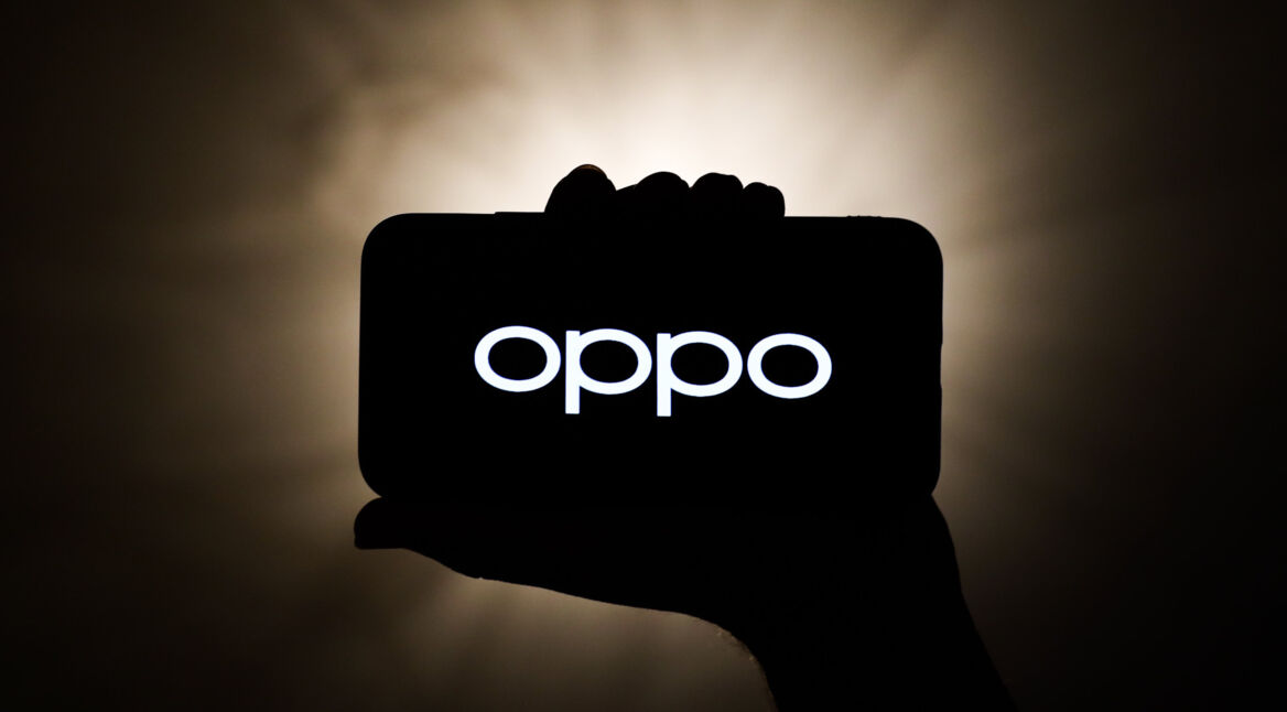 Silhoutte einer Hand hält Smartphone mit OPPO-Logo vor dunklem Hintergrund mit Lichtquelle