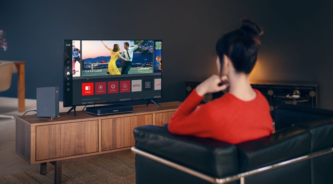 Frau sitzt auf Sofa und schaut GigaTV