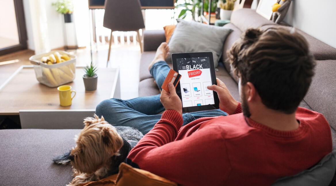 Mann liegt auf der Couch und schaut nach Angeboten am Black Friday
