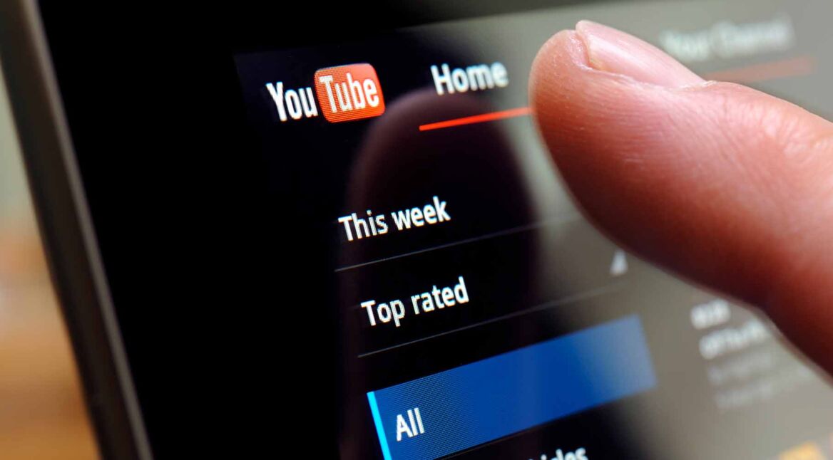 Ein Finger tipps auf einen Bildschirm bei geöffneter YouTube-App