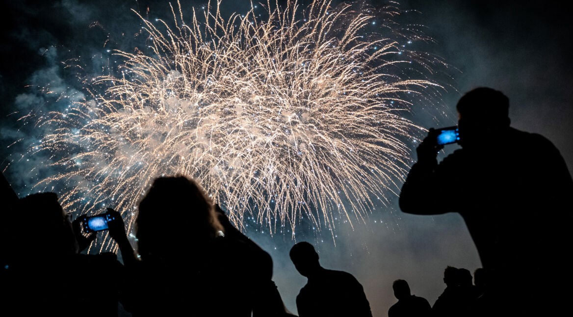 Silhouetten von Menschen, die ein Feuerwerk mit ihren Smartphones filmen