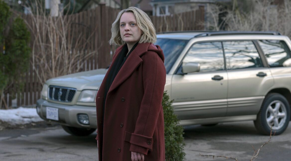 Eine Frau im roten Mantel vor einem SUV.