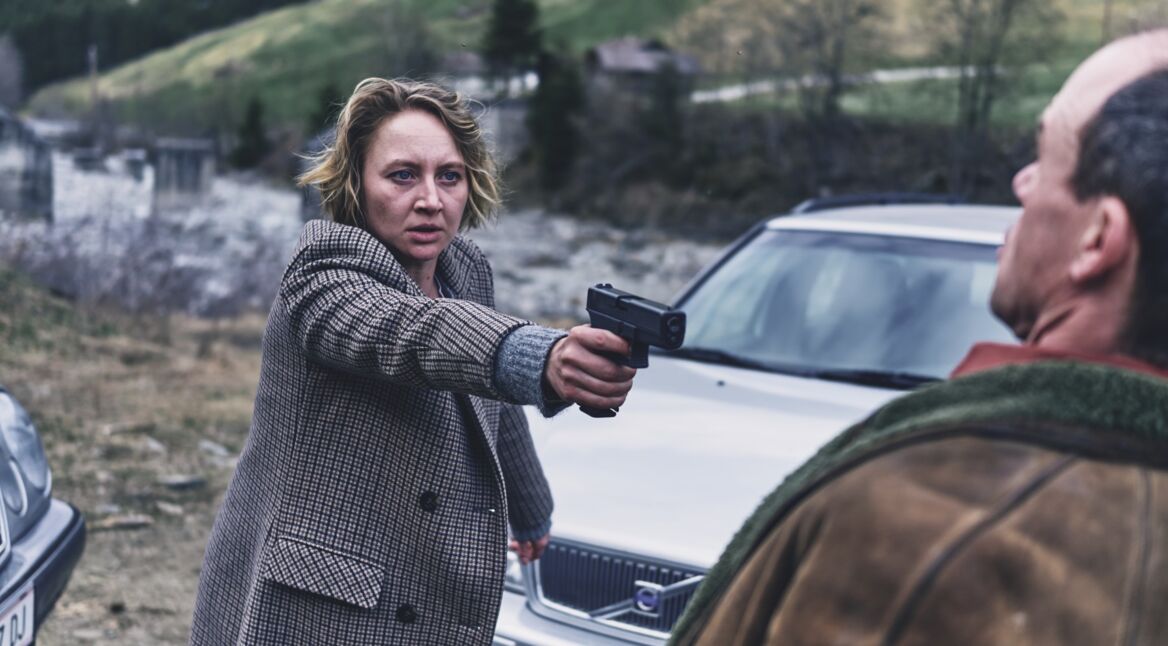 Eine Frau bedroht einen Mann mit der Waffe.