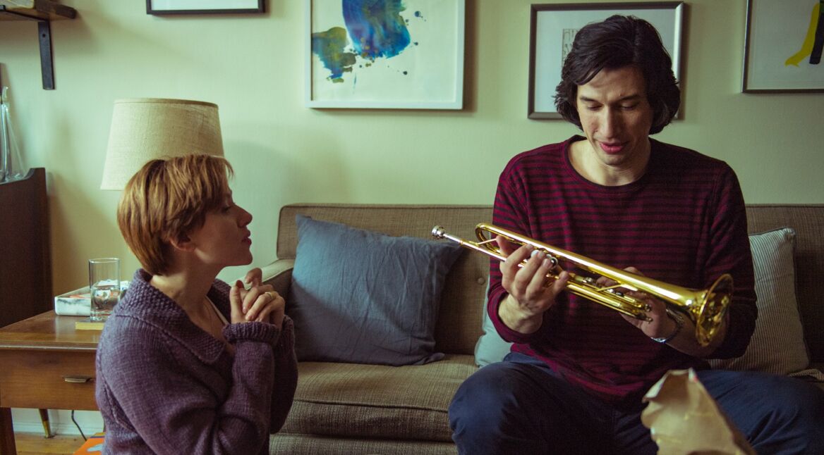 Eine Frau kniet, ein Mann hält eine Trompete.