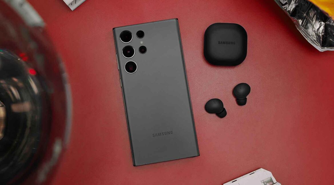 Das Samsung Galaxy S23 Ultra liegt mit der Vorderseite auf einer roten Fläche neben Samsung-Kopfhörern