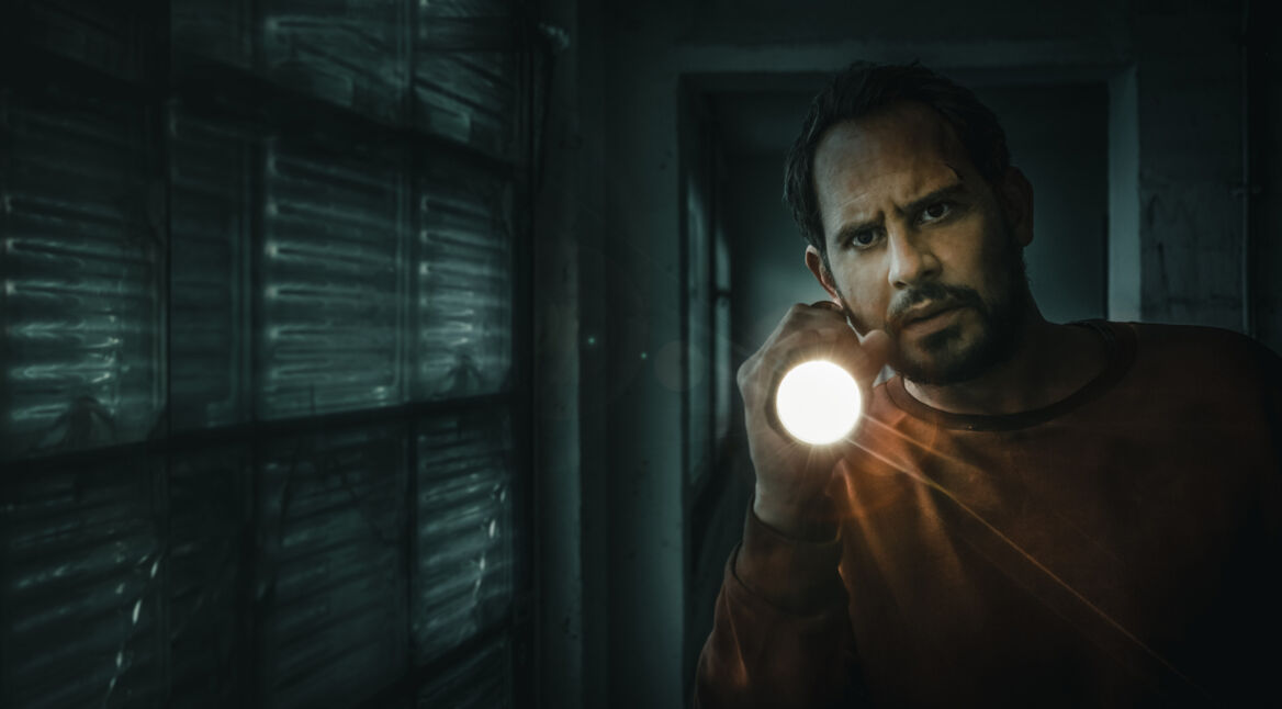 Moritz Bleibtreu hält eine Taschenlampe in die Kamera und schaut skeptisch