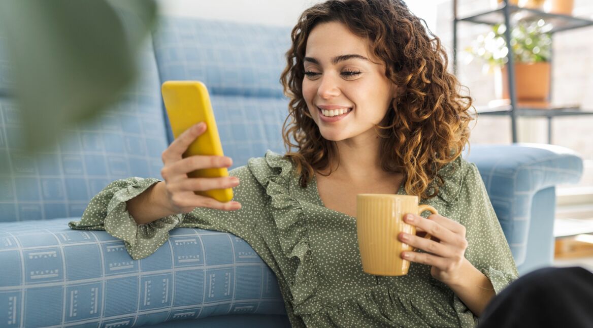 Junge FRau mit Handy auf der Couch