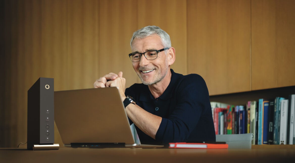 Ein Mann sitzt an seinem Laptop und loggt sich mit seinem Browser in das Router-Menü ein