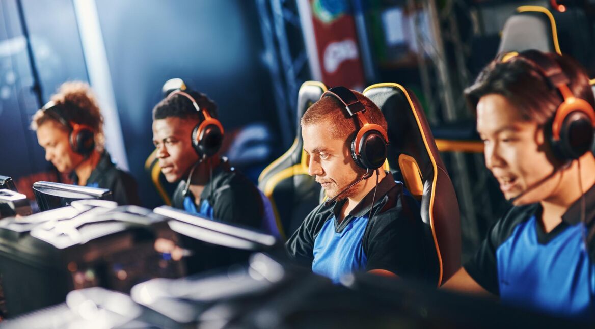 Vier Gamer:innen sitzen vor ihren Rechnern und spielen