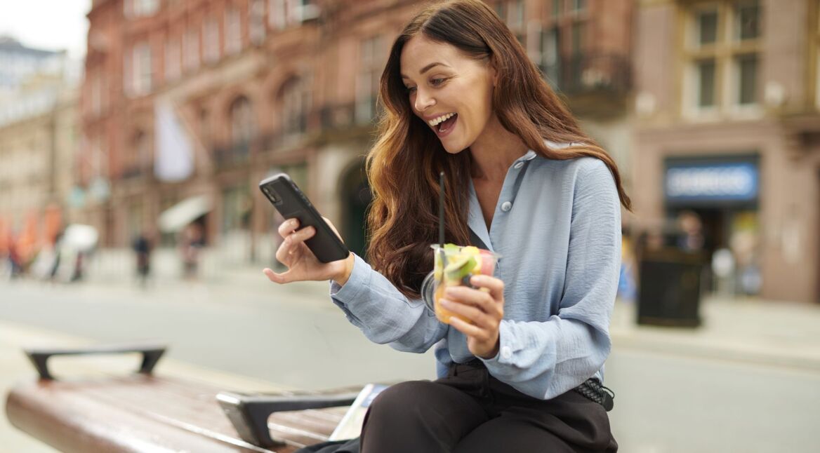 Frau schaut lächelnd auf ihr Handy