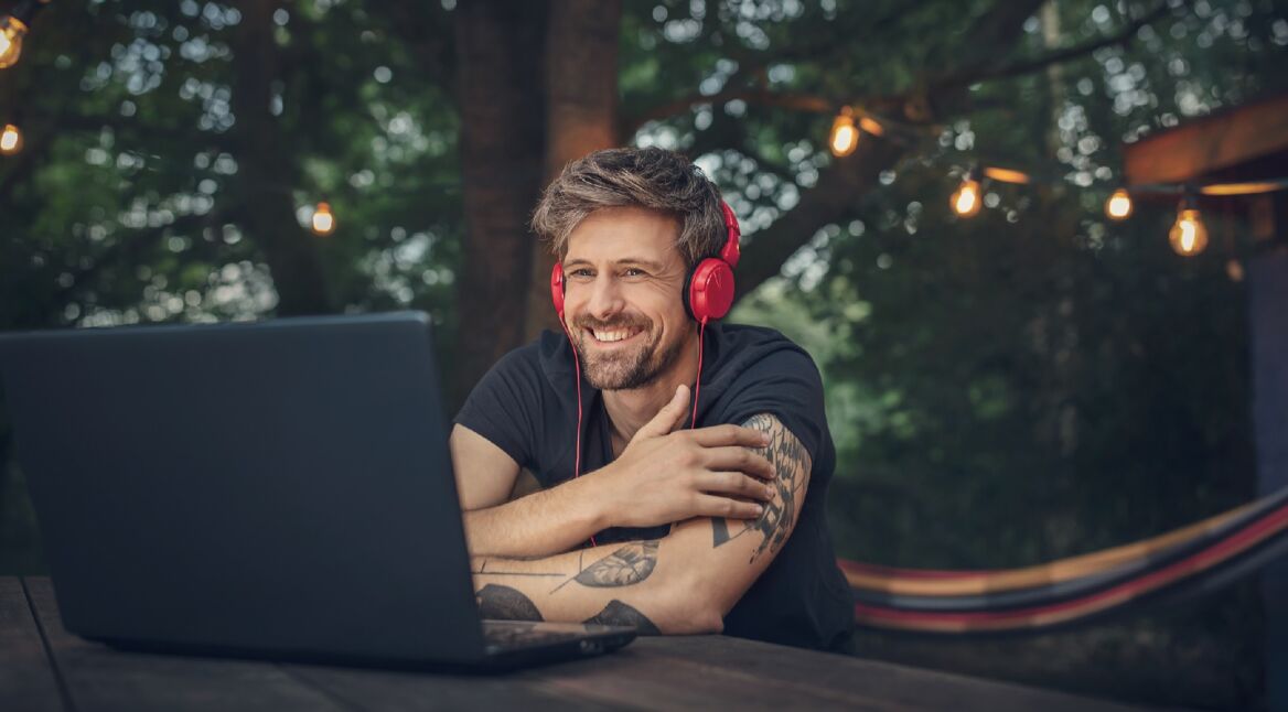 Mann mit Kopfhörern vor Laptop