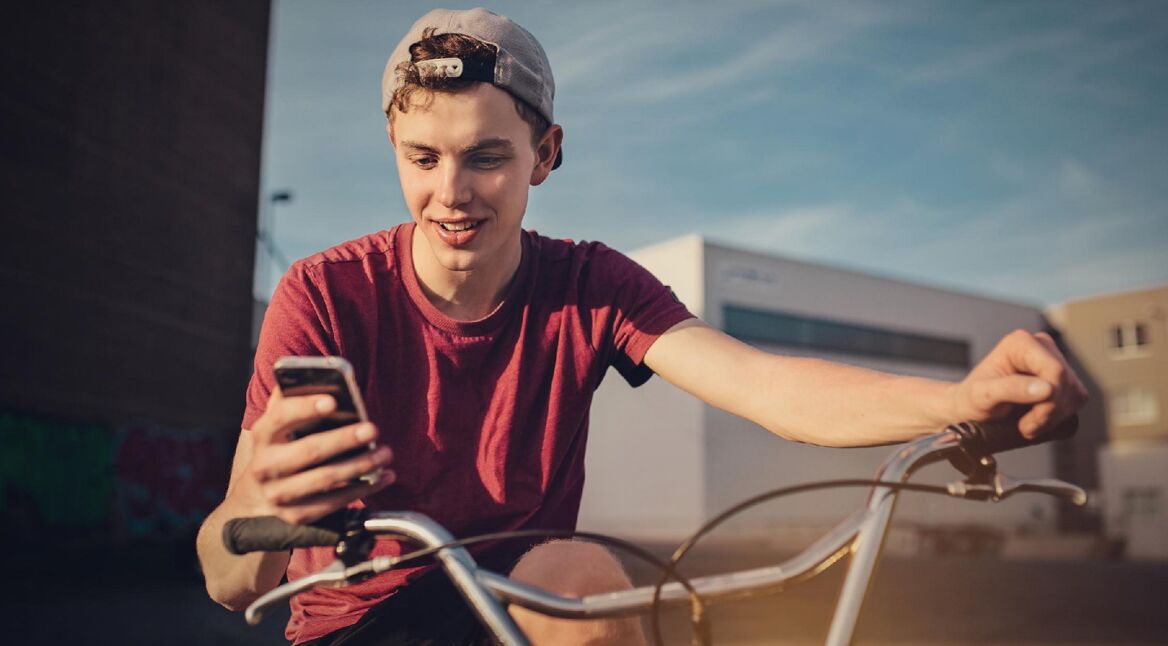 Junge auf Fahrrad mit Smartphone