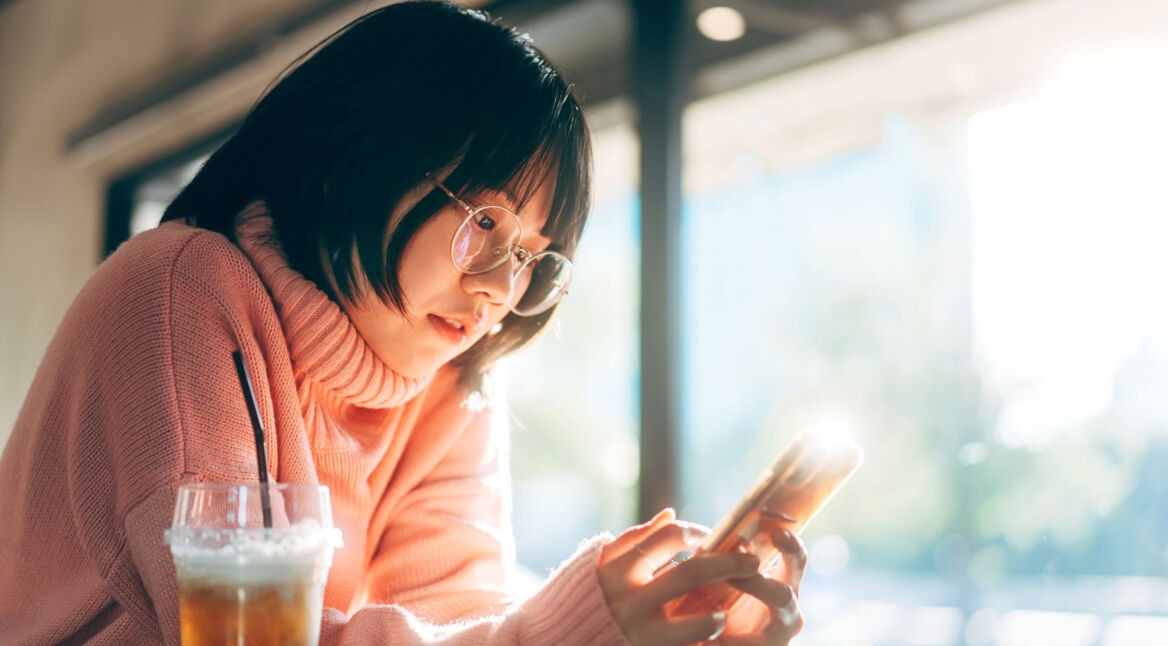 Mädchen schaut auf rosa Smartphone