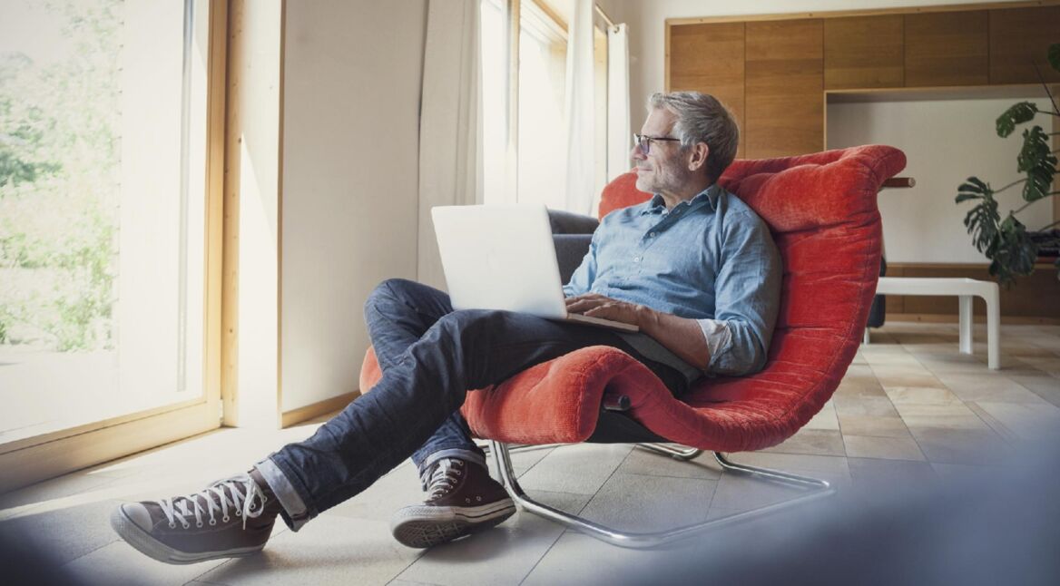 Mann auf Sessel mit Laptop