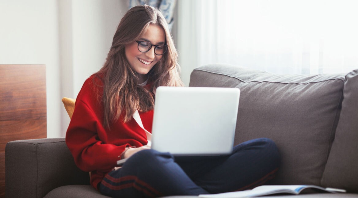 Studentin auf dem Sofa an ihrem Laptop beim Lernen