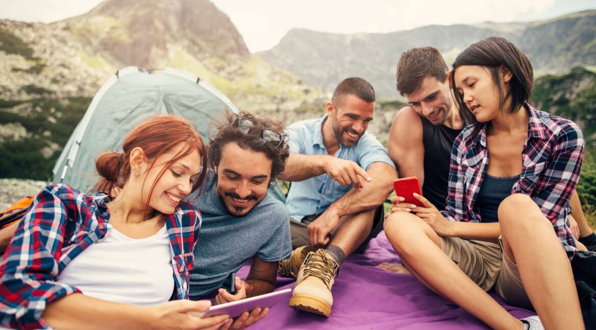 Junge Leute beim Wandern auf einem Berg, schauen gemeinsam auf ein Handy