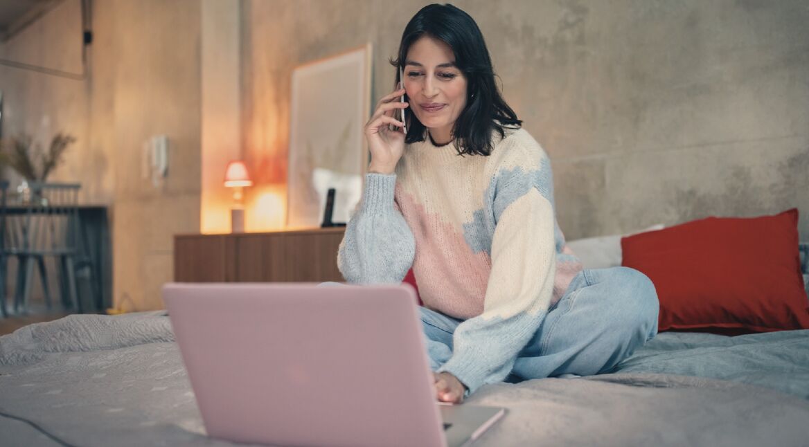 Frau am Telefon vor Laptop