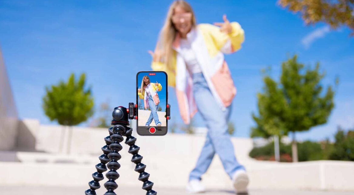 Ein Teenagermädchen filmt sich selbst mit einem Handy auf einem Stativ