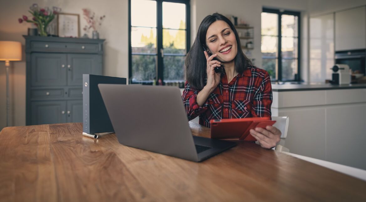 Frau am Telefon vor Laptop