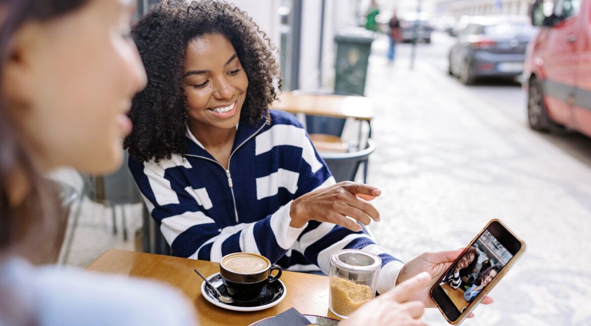 Zwei Frauen schauen sich Fotos auf einem Handy an.