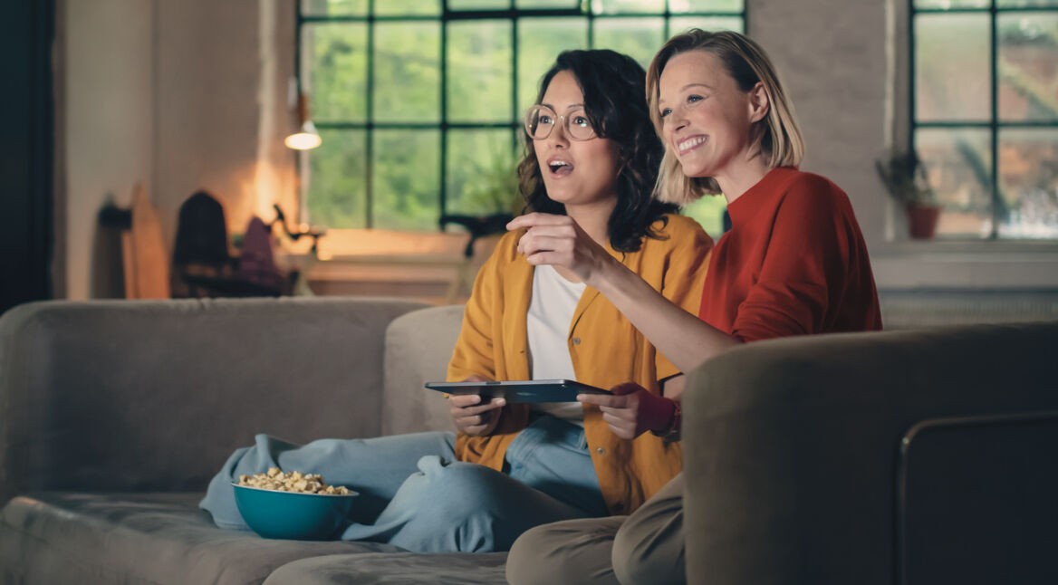 Zwei Frauen schauen gemeinsam GigaTV-Mediatheken für True-Crime-Fans